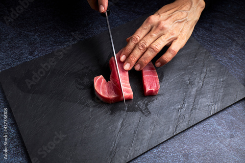 Female cook preparing a piece of bluefin tuna to make sushi. Asian food concept