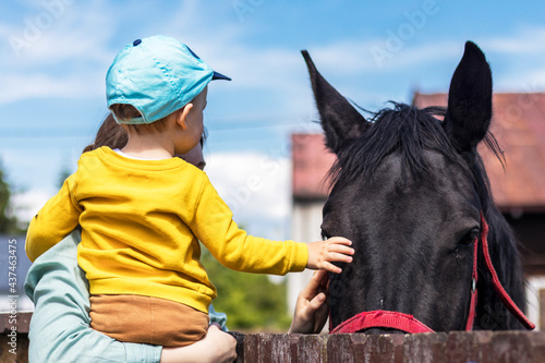 Dziecko z matką głaszczące konia.