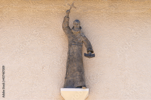Santa Inez, CA, USA - May 26, 2021:San Lorenzo Seminary. Closeup of gray preaching monk statue on beige wall above main entrande door to the church