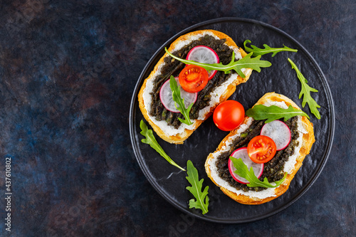 Healthy food. Avocado toasts with avocado, cream cheese and radish. Toasts with avocado, arugula and cherry tomatoes on a dark background. Copy space. Top view