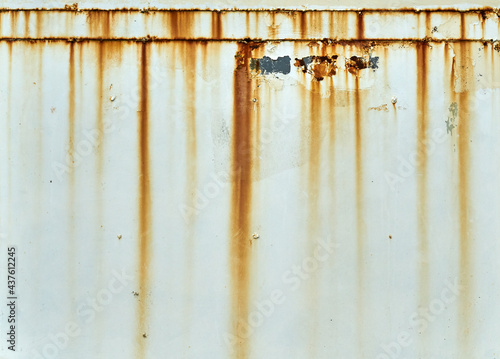 Orange rust streaks down a white wall