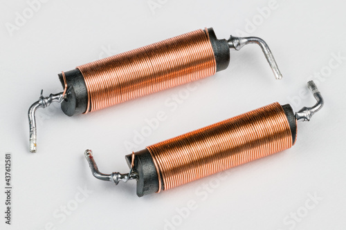 Two solenoids with helical copper wire wound on black coil on white background. Close-up of electronic components with magnetic field inside. Long cylindric inductors with ferrite core. Electromagnet.