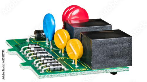 Electronic components on green circuit board isolated on white background. Row of semiconductor diodes, colored thermistors and metal oxide varistors or black connectors in data link surge protector.