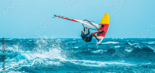 watersport: windsurfer jumping among waves of the blue ocean during a summer vacation 