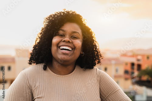 Happy Latin young woman having fun laughing in front of camera on house patio