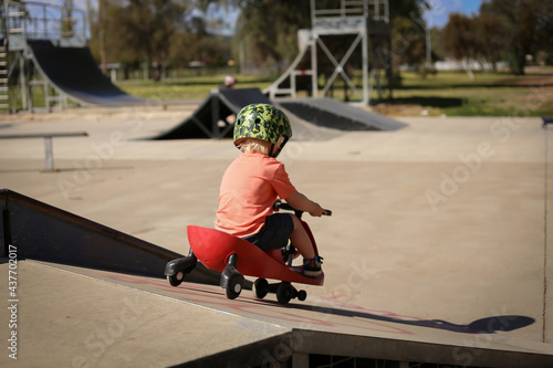 Happy little boy playing on ride on cart at skate park