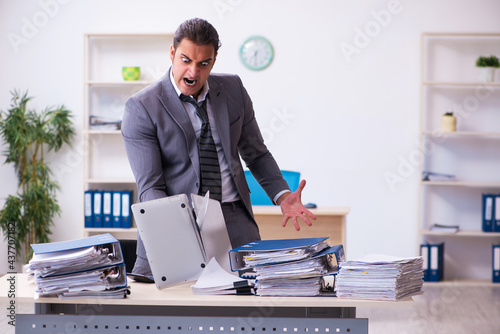 Young employee angry with excessive work holding knife