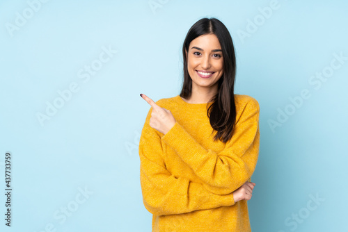 Young caucasian woman isolated on blue background pointing to the side to present a product