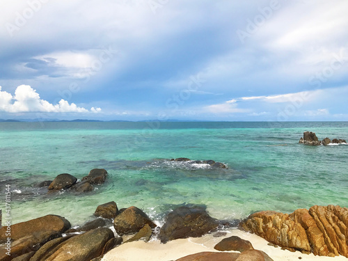 Beautiful seascape summer background. Many rocks on sand beach on the sea and sky background on a sunny day.