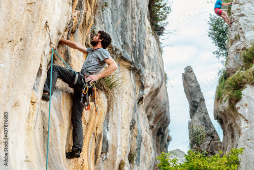 Man with rope, harness, and hooks climbing a vertical rock wall in the mountain. mountain sports and adventure