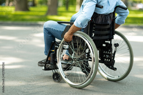 Cropped view of young black disabled man in wheelchair enjoying summer at green park, closeup