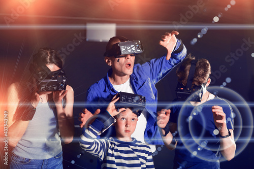 Emotional young parents with two teenage sons having fun with vr headset goggles. Concept of new technology and family entertainment. Toned image with visual effects