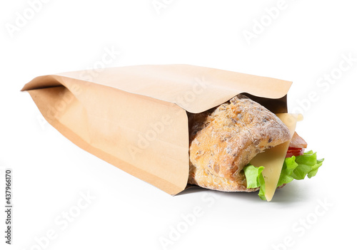 Bag with tasty ciabatta sandwich on white background