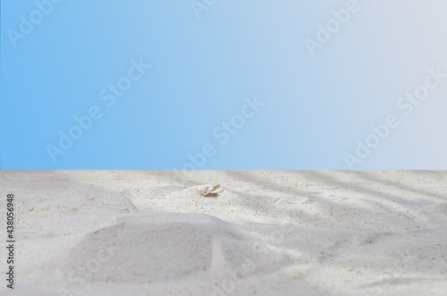 Advertising background of cosmetic products. Sea sand on a blue background with shadows. Blank mockup to showcase product packaging. Selective focus, copy space