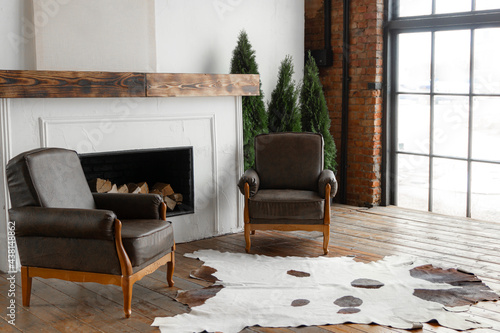 Side view of spacious white country house interior in eco style with teo chairs and fireplace