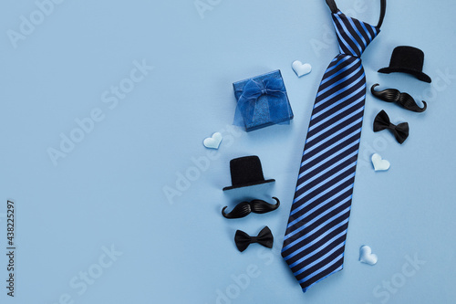 Father's Day poster or banner with necktie and decorations on blue background. Greetings for Father's Day. Flat lay styling.