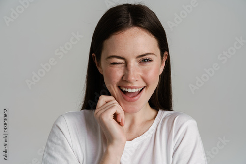 Young brunette woman winking and laughing at camera