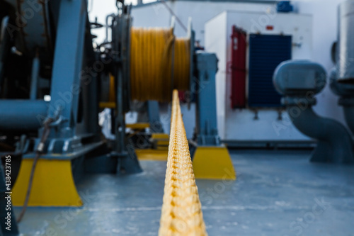 Marine hydraulic winch for mooring operations with yellow ropes wound around it.