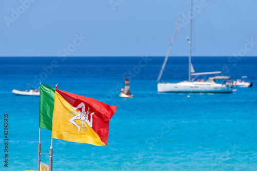 flag of the region in sicily blowing in the wind on the clear sea between boats