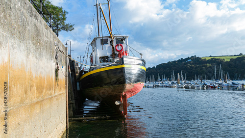 Fishing boats moored in a small harbour in the town of Dartmouth in Devon, UK. Southwest England, British sea life. River Dart.