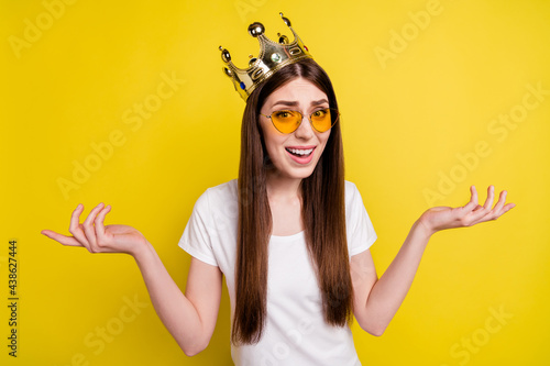 Portrait of attractive arrogant selfish girl wearing crown don't know isolated over bright yellow color background