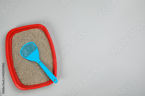 Cat litter tray with filler and scoop on light background, top view. Space for text