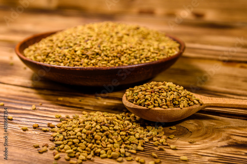 Ceramic plate and spoon with fenugreek seeds on wooden table