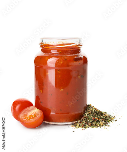 Glass jar of tasty tomato sauce and spices on white background