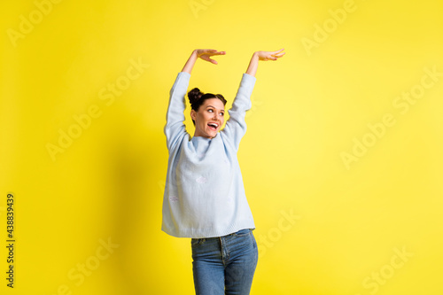 Photo of lady raise arms look side empty space open mouth wear blue sweater jeans isolated yellow background