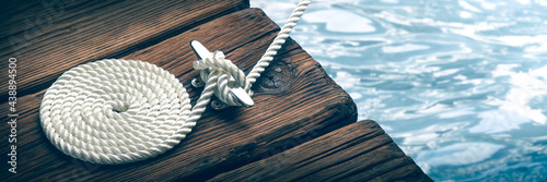 Coiled Boat Rope Secured To Cleat On Wooden Dock 