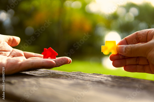 Left hand holding red and yellow model car holding.Have a solar background. Home loan with car exchange or trade in business or real estate.For family happiness. 