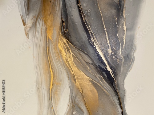 Abstract grey art with gold — black and white background with beautiful smudges and stains made with alcohol ink and golden paint. Grey fluid texture resembles marble, smoke, watercolor or aquarelle.