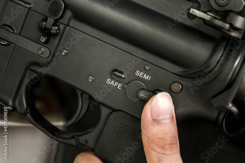Finger selecting Rifle gun selective switch on safe mode position