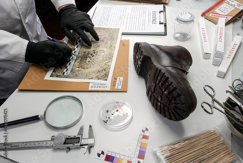 Police scientist examines shoe sole strips related to crime lab murder, concept image