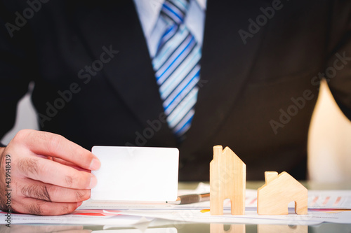 Businessman hold credit cards with wooden home and contracts in the office for investment a real estate and buying or a loan for new house in the future concept.