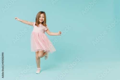 Full size body length little fun cute kid girl 5-6 years old wears pink dress dancing isolated on pastel blue color background child studio portrait. Mother's Day love family people lifestyle concept.