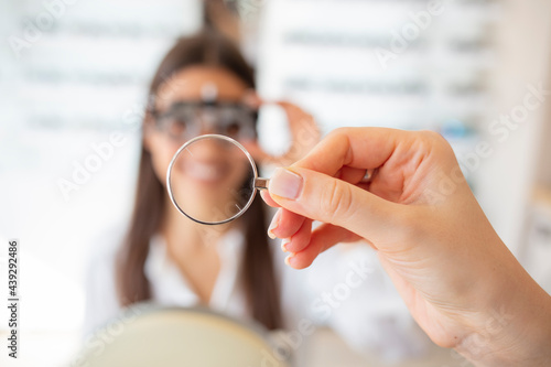 Optometrist examining female patient with phoropter in ophthalmology clinic. Checking patient vision at eye clinic. Ophthalmologist examining attractive woman with optometrist trial frame