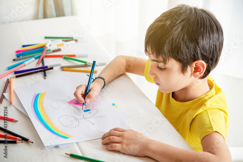 child draws his family on a piece of paper with colored pencils. Concept of child psychology.