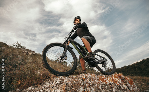 Confident cyclist with e bike in mountains