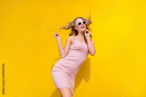 Portrait of attractive cheerful dreamy wavy-haired girl air blowing posing clubbing isolated over bright yellow color background