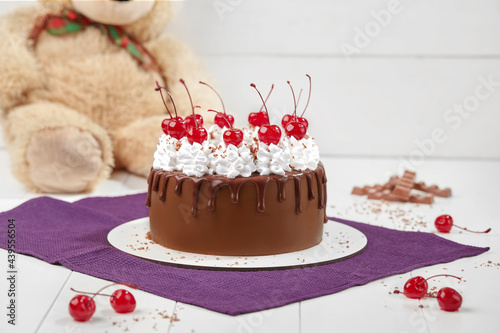 Chocolate sponge cake with whipped cream and maraschino cherries