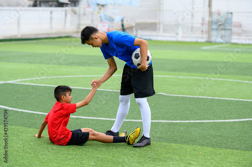 Asian teenager Football Players pulls the hand of a fallen player.
