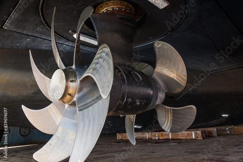 The bottom of a ship supported in dry dock with azimuth propulsion and twin propellers aft.