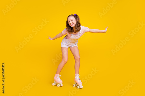 Full length body size photo schoolgirl riding rollers in summer isolated bright yellow color background