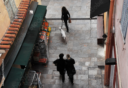 People walking on the street in Francheville, France. Photo from above. Woman walking her white dog.