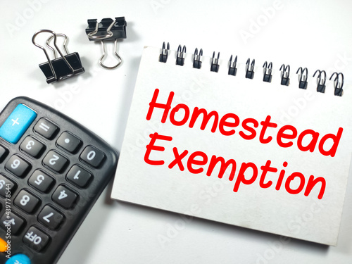Education concept. Text Homestead Exemption on notebook with paper clips and calculator on white background.