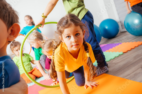 Curly girl crawling on colorful floor through hula hoops