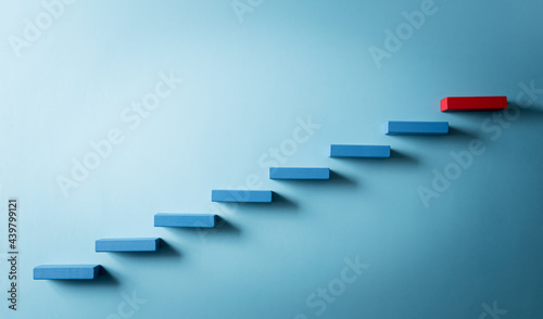 Concept of building success foundation. Yellow and red wooden block stacking as step stair, Success in business growth concept on pastel blue background.