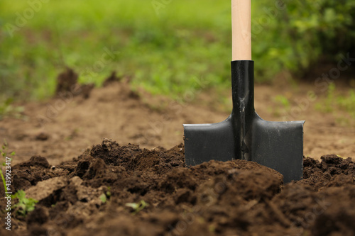 Shovel in soil outdoors, space for text. Gardening tool