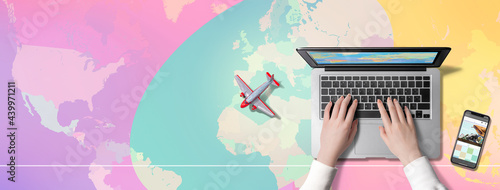 世界地図を背景に、パソコンを操作する人、旅行会社のサイトを表示するスマートフォン、飛行機。海外旅行の予定を立てている人のイメージ。もしくはパソコンで、バーチャル世界旅行を楽しむ人のイメージ
